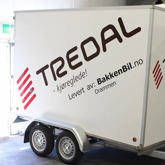Tredal-henger med boksform med stor Tredal-logo og reklame for Bakken Bil